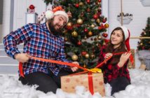father and daughter with presents in front of Christmas tree