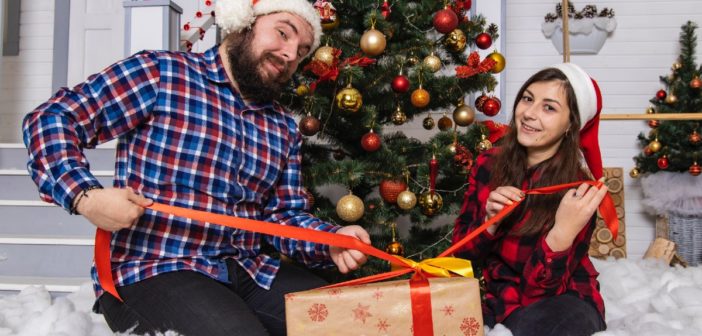 father and daughter with presents in front of Christmas tree